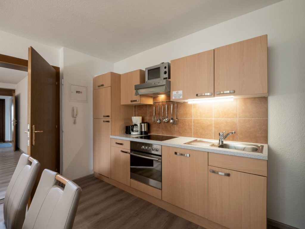 Moderne Kücheneinrichtung mit Holzschränken und Geräten aus Edelstahl.