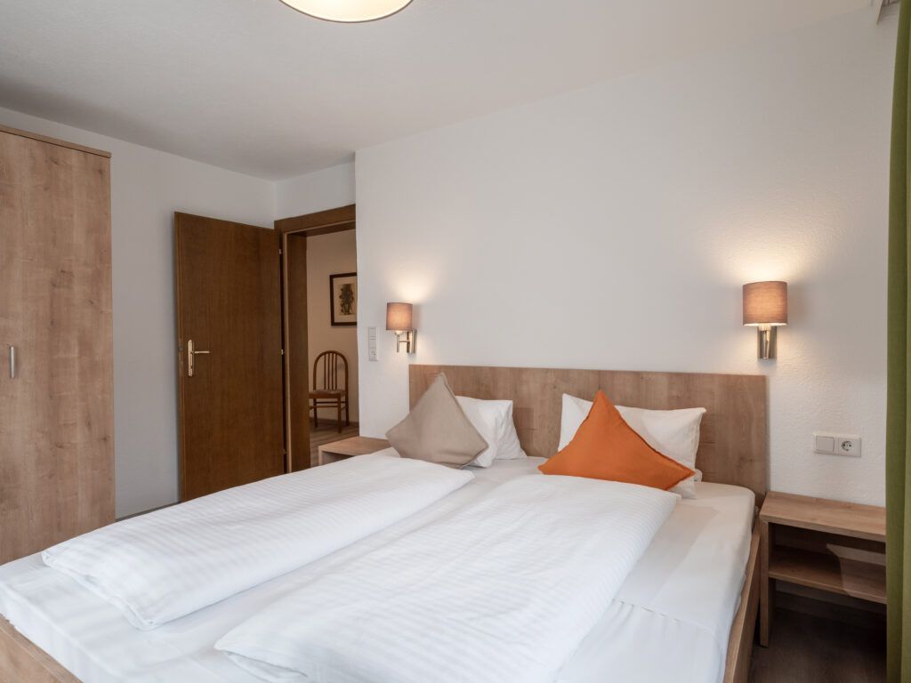 Ein ordentliches Hotelzimmer mit zwei Einzelbetten und einfacher Einrichtung.